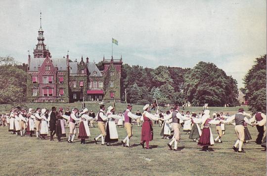 Folkdansare på gräsmattan framför slottet Kulla Gunnarstorp